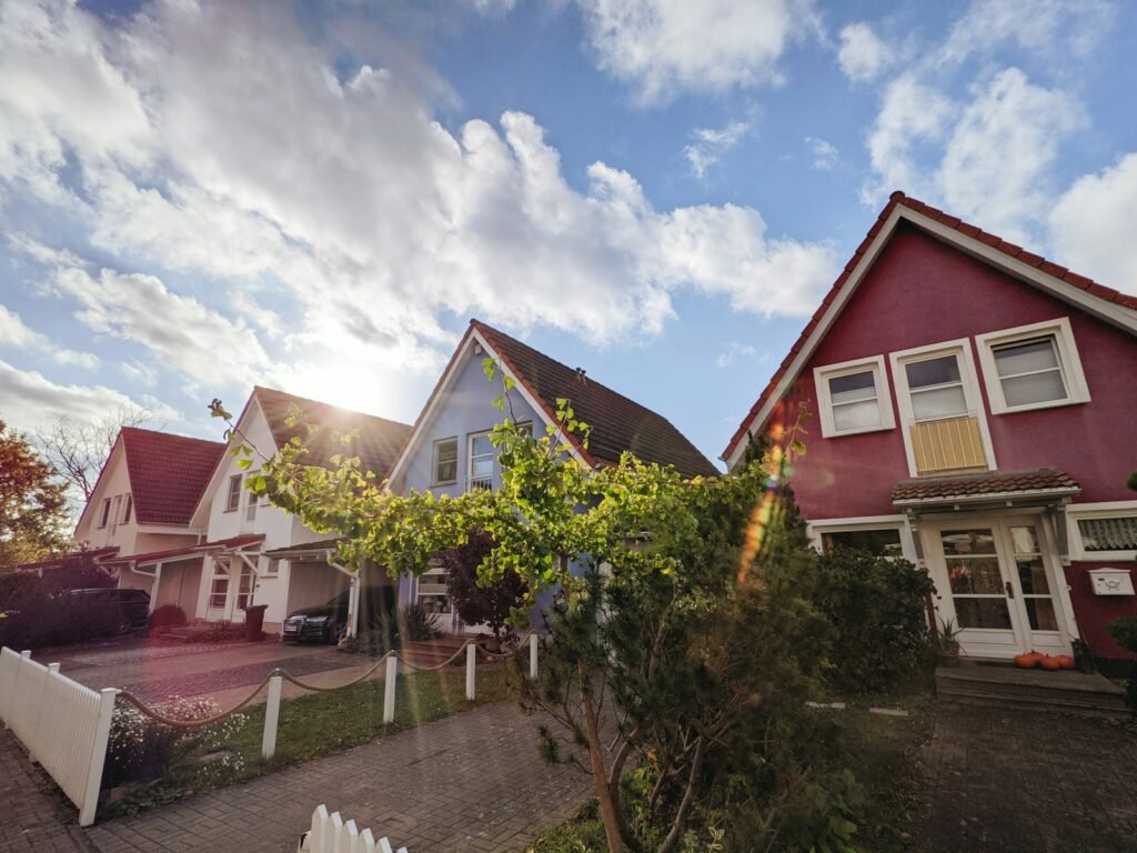 home mortgage, green trees near red and white house under blue sky during daytime