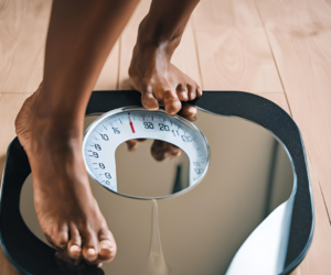 ozempic personality changes, A close-up of a scale with a person looking at their reflection in the mirror, possibly indicating a change in how they view themselves after losing weight or altering their body image.