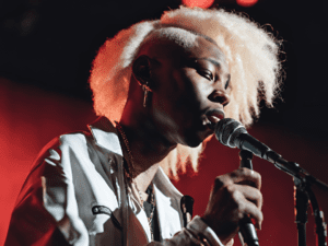 albino black individual, A photo of Joey A performing on stage with a microphone, expressing confidence and passion. The image could be styled in a way that reflects his hip-hop/R&B musical blend, showing him as an inspiring figure for young albino black indi